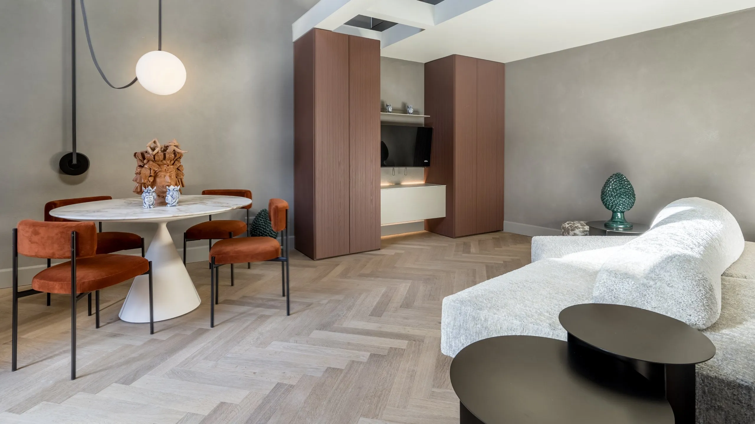 Soggiorno Suite Executive Basil Conrad: tavolo in marmo con sedie arancio, divano moderno e pavimento in parquet a Villa Conrad.