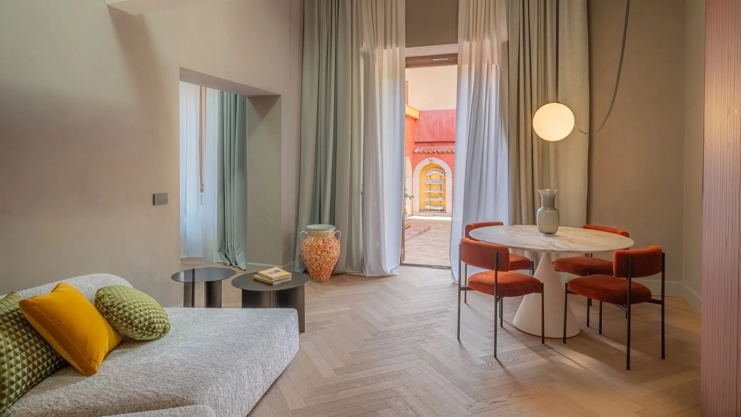 Zona living Junior Suite Executive Basil Conrad a Taormina con tavolo in marmo, arredi di design e accesso al cortile.
