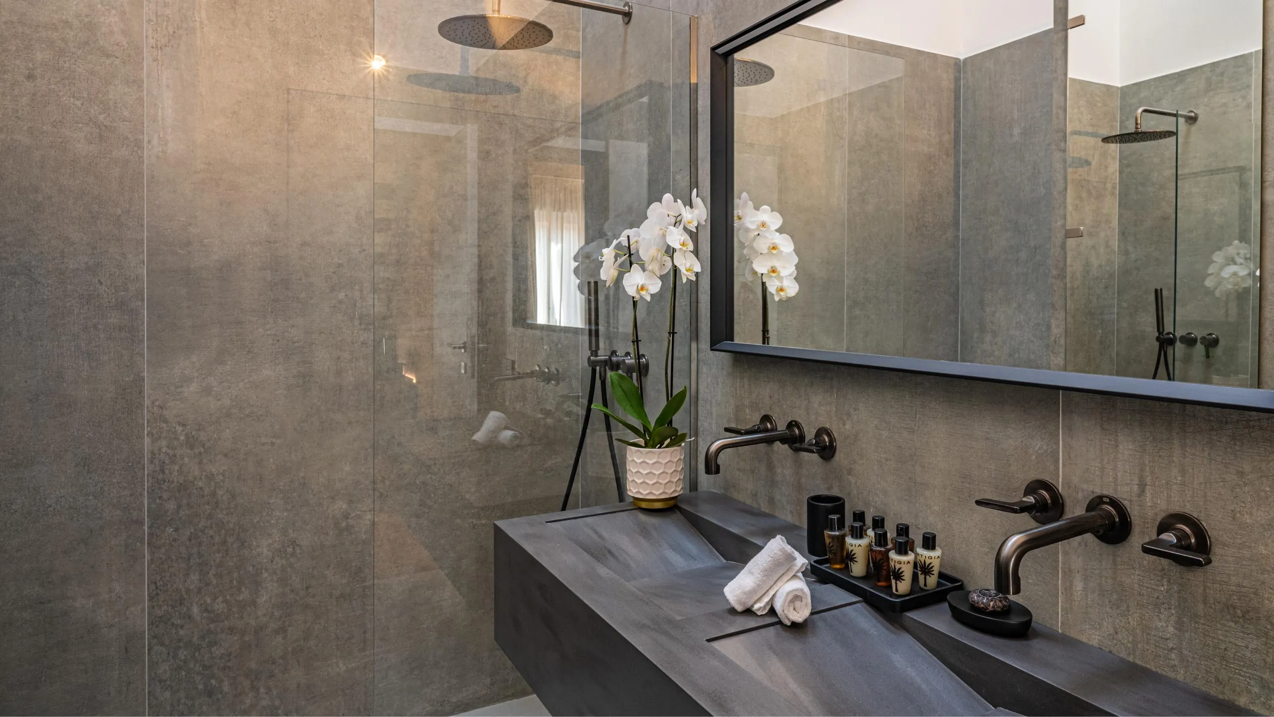 Bagno Suite Lady Trevelyan Villa Conrad: lavabo in resina scura, ampia doccia walk-in e orchidea bianca a Taormina.