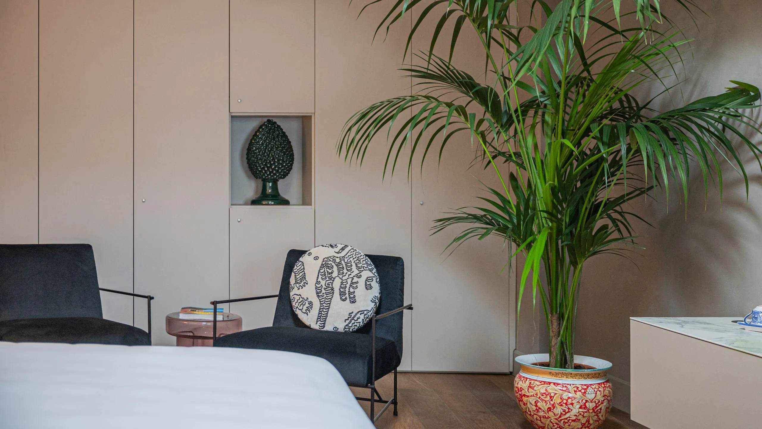 Angolo relax Suite Byron: poltrone in velluto nero, vaso in ceramica siciliana e pigna verde decorativa.