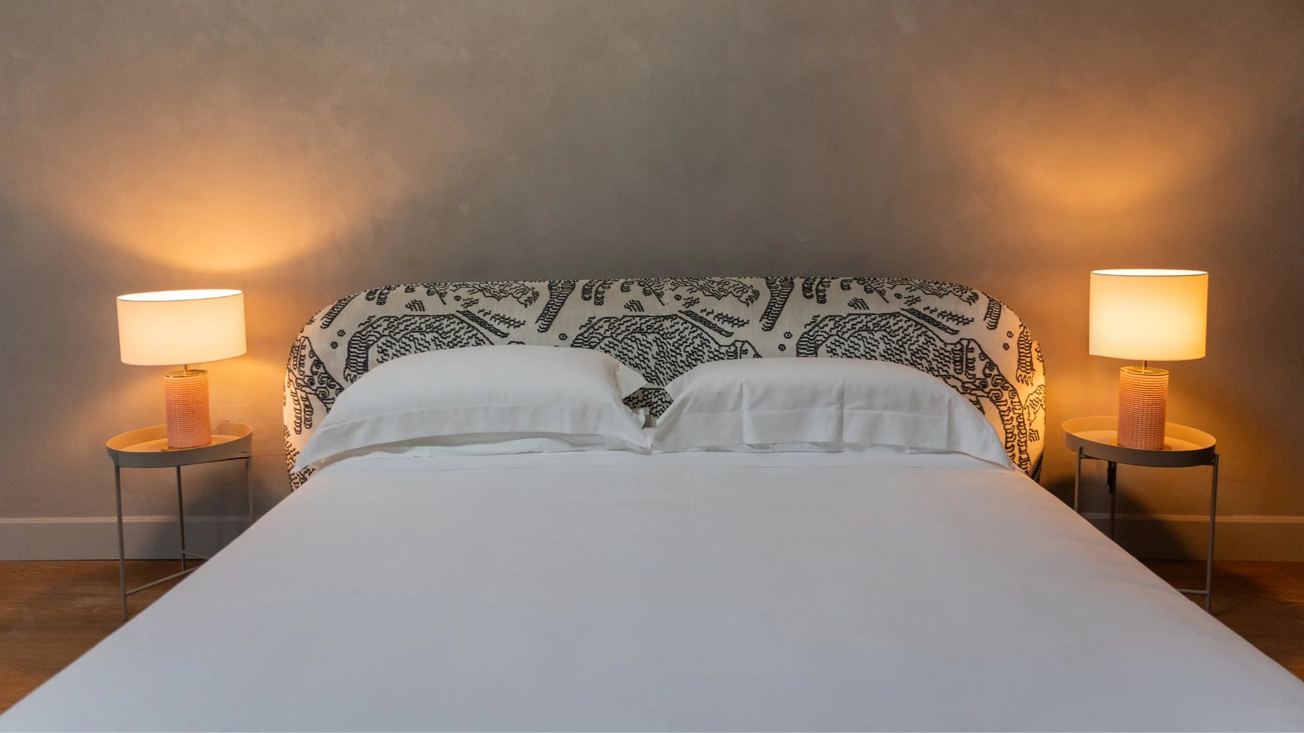 Letto matrimoniale su soppalco nella Junior Suite Sitwell: soffitto mansardato, travi a vista e luci di design.