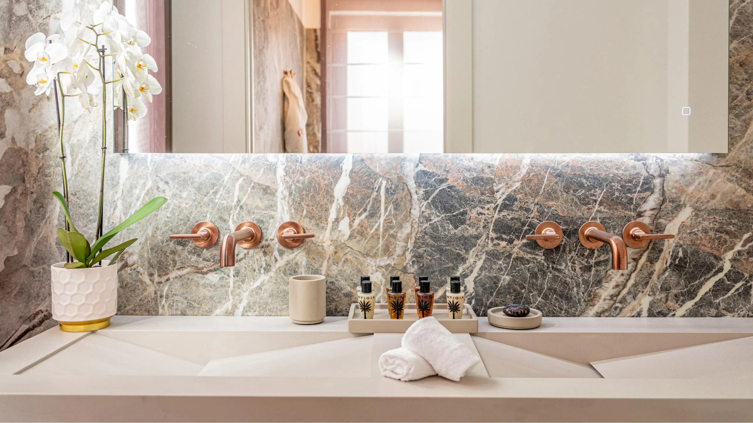 Bagno Suite Oscar Wilde: lavabo a ciotola, pareti con motivo a spina di pesce e specchio tondo a Villa Conrad.