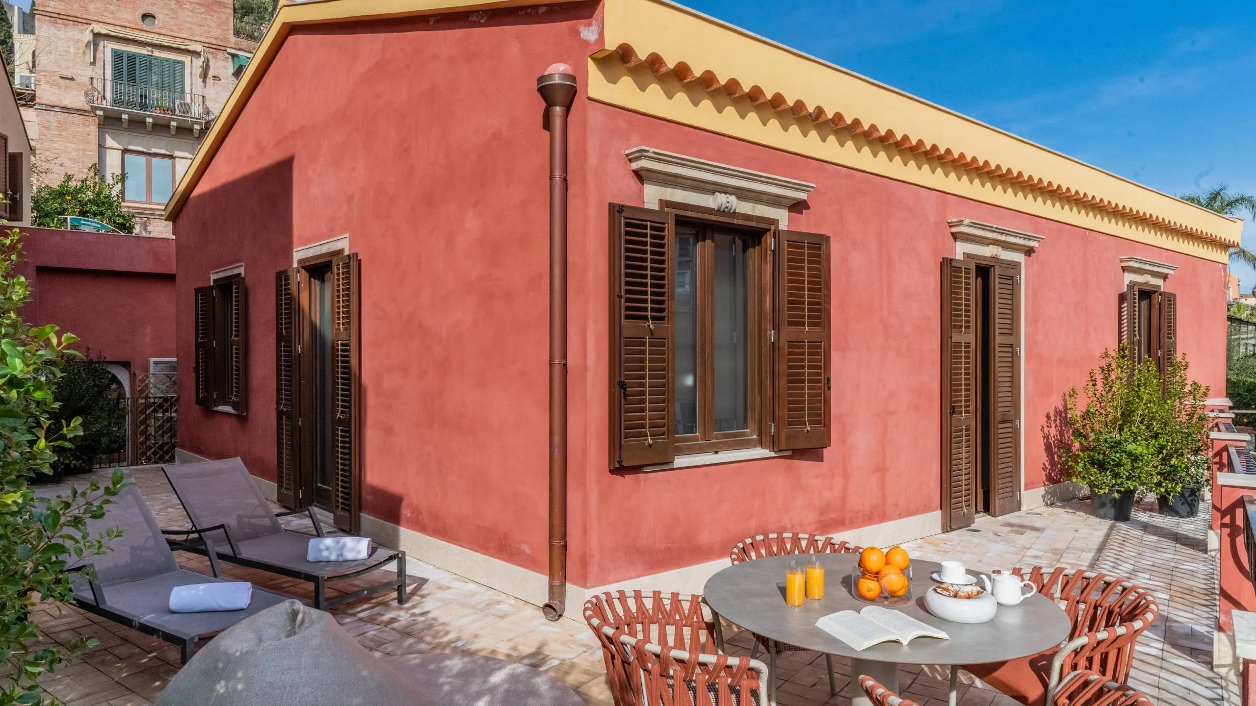 Terrazza privata Suite Oscar Wilde: tavolino di design, poltrone e vista sui tetti di Taormina a Villa Conrad.