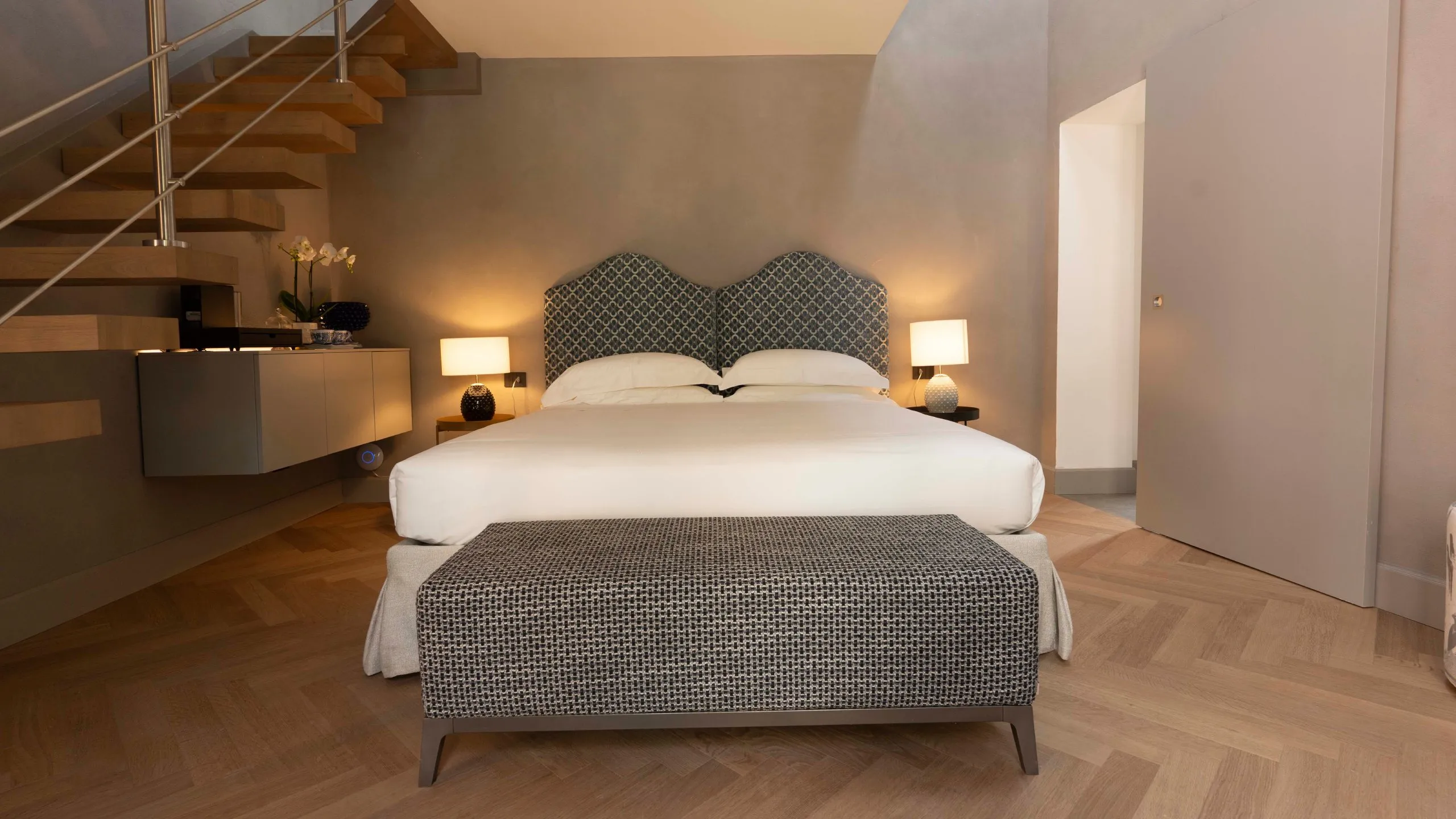 Camera Deluxe Goethe: letto matrimoniale con testiera azzurra, scala a sbalzo e parquet a Villa Conrad Taormina.