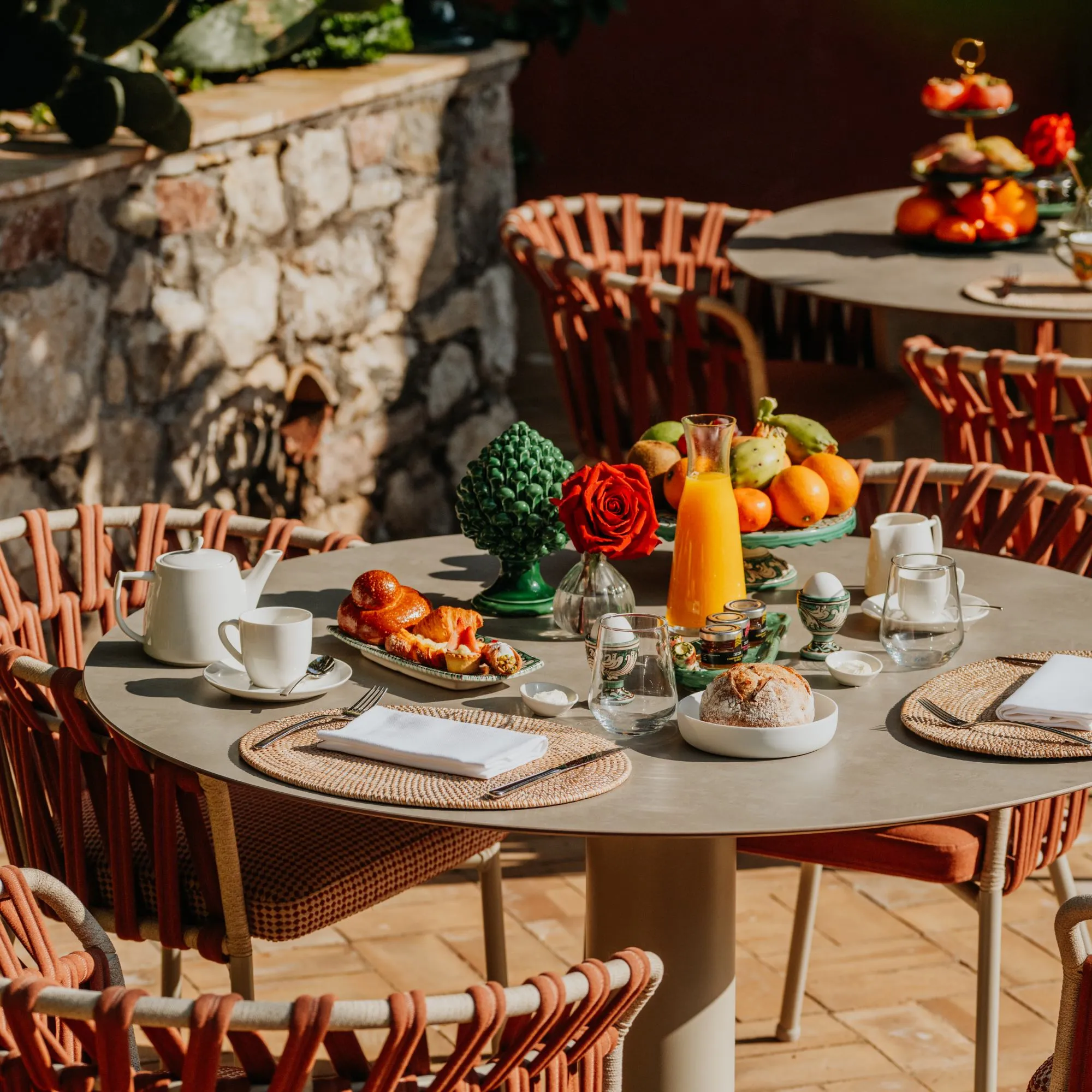 Colazione tipica siciliana all'aperto a Villa Conrad Taormina con spremuta fresca, brioche e pigna in ceramica.