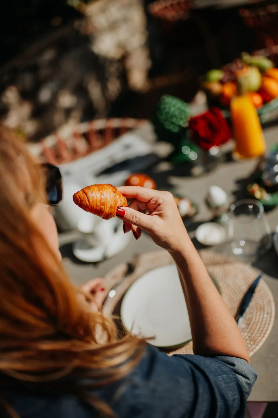 Momento colazione a Villa Conrad Taormina: ospite gusta un cornetto artigianale in terrazza al sole.